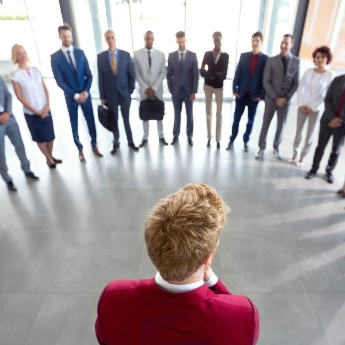 A man in red jumper watch his team gathered in front of him
