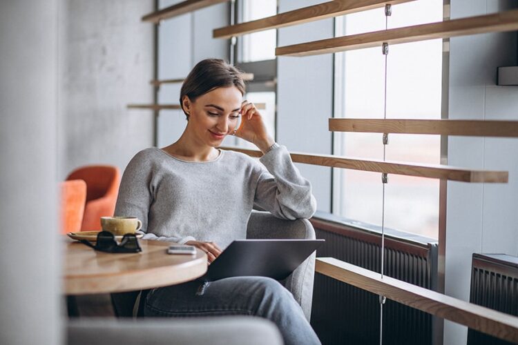 A Woman entrepreneur sitting on a bar, watching her Laptop while smiling, using AI for her projects