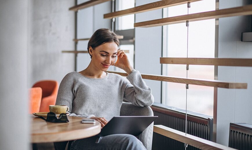 A Woman entrepreneur sitting on a bar, watching her Laptop while smiling, using AI for her projects
