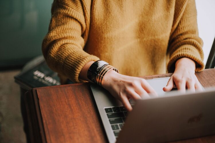 Woman's hands typing on a laptop
